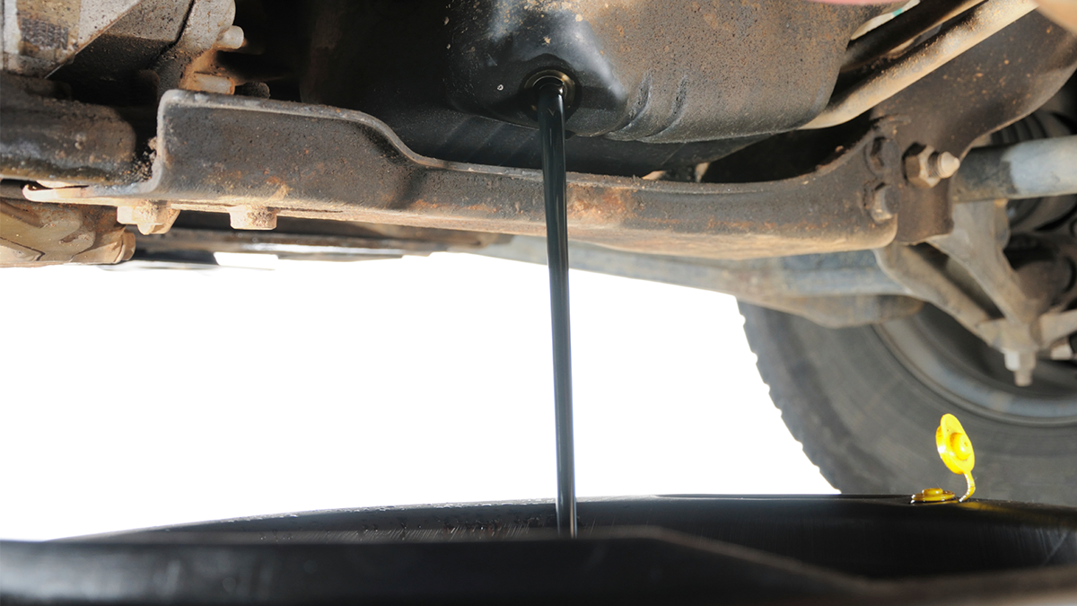 Motor oil draining from an engine into an oil pan.