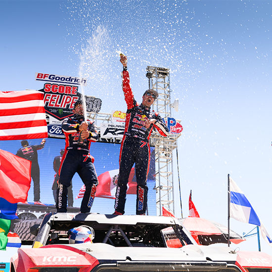 Menzies celebrates victory with champaign while standing on his truck roof