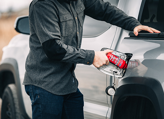 Person adds bottle of AMSOIL P.i. to his truck's gas tank.