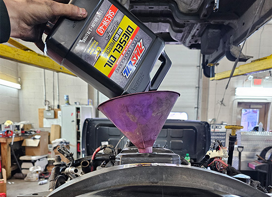 AMSOIL Signature Series 5W-40 100% Synthetic Max-Duty Diesel Oil is poured into a vehicle at Backwoods Diesel in Pennsylvania.