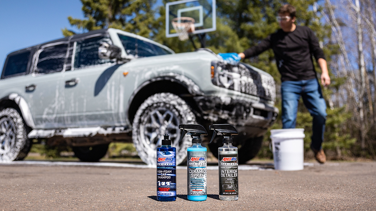 Man washes his vehicle with AMSOIL Car Care products in the foreground.
