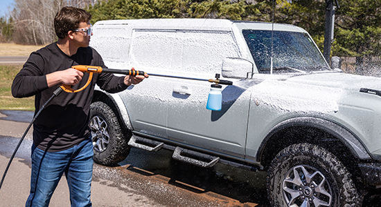 A man applies AMSOIL High-Foam Car Shampoo to his vehicle using a foam cannon.