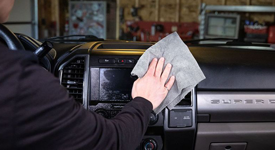 Person wipes away a display screen using AMSOIL Interior Detailer.