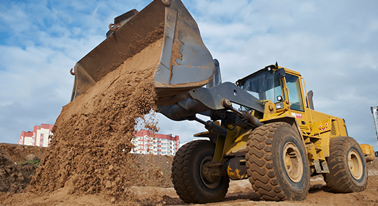 A large front-end loader performs dirt work at a construction site.