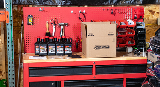 An AMSOIL oi-change kit sits on a workbench next to a pickup truck.