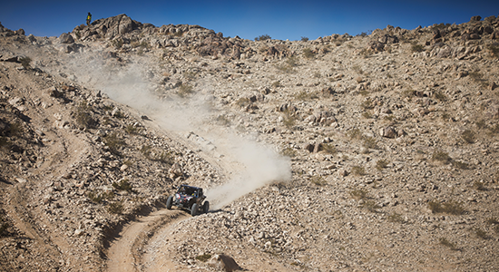 UTV drives hard on a desert mountain trail.