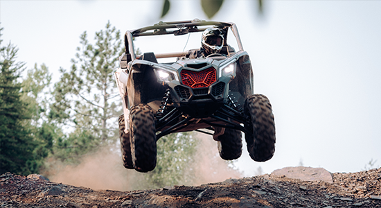 UTV rips down a trail, launching itself off a hilltop.