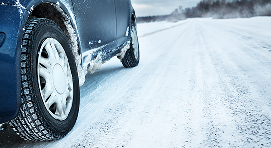 A car is stranded along a wintery country road.