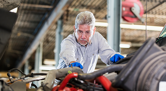 A mechanic inspects the upper region of a vehicle.