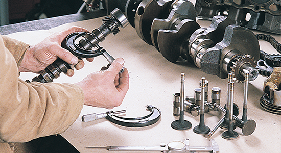 A mechanic measures the lobes on a camshaft.