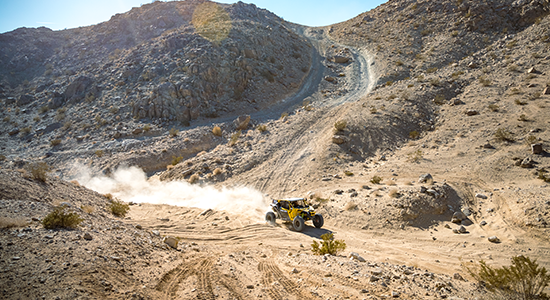 A UTV descends a steep slope in a western landscape.