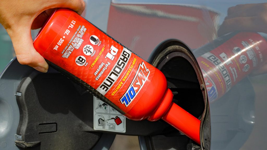 Bottle of AMSOIL P.i. gasoline additive is poured into a vehicle.