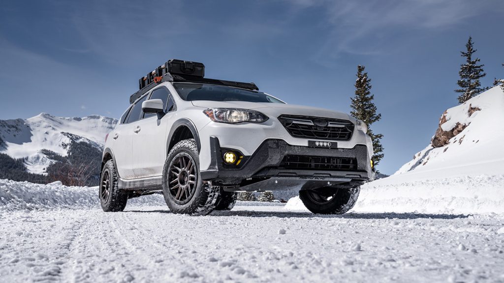 A Subaru Crosstrek sits in a snowy parking space in the mountains.