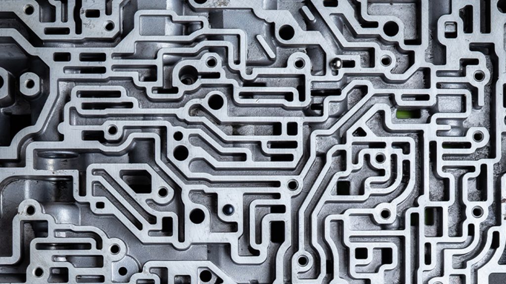 A close up of the many channels and valves in an automatic transmission valve body.