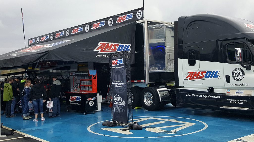 AMSOIL display and hauler with a Motorcycle Mechanics Institute banner reading “Proud Partners in Supporting Tomorrow’s Technicians”
