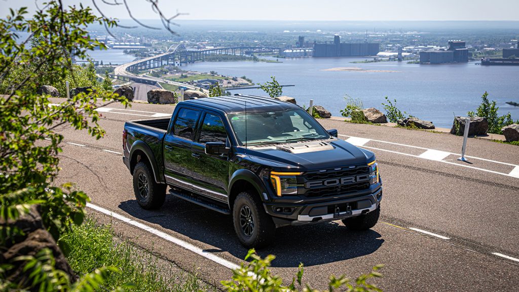 A 2025 Ford F-150 Raptor drives along a scenic road.