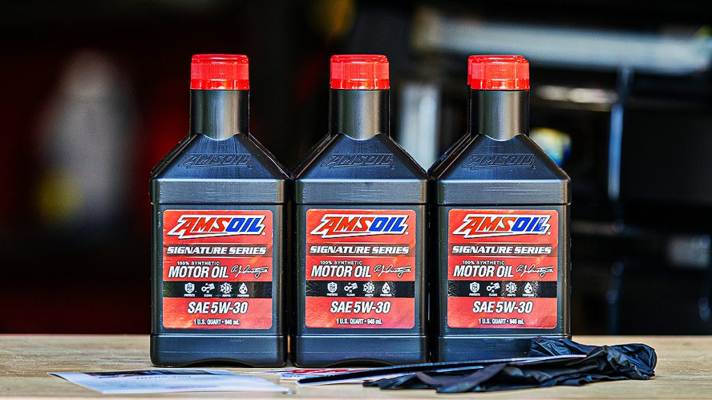 Three quarts of AMSOIL Signature Series 100% Synthetic Motor Oil 5W-30 on a workbench